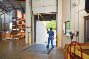 DG Series loading dock gate with vertical lift being lifted by an employee at an open dock